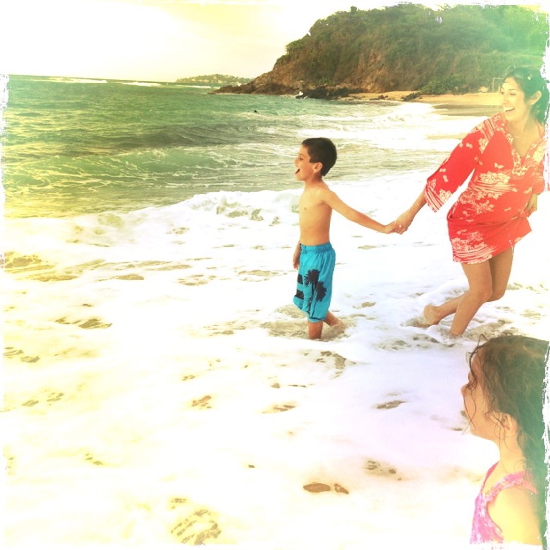 Maria in a red kimono coverup, holding her son's hand in the surf at Vieques, her daughter in the foreground
