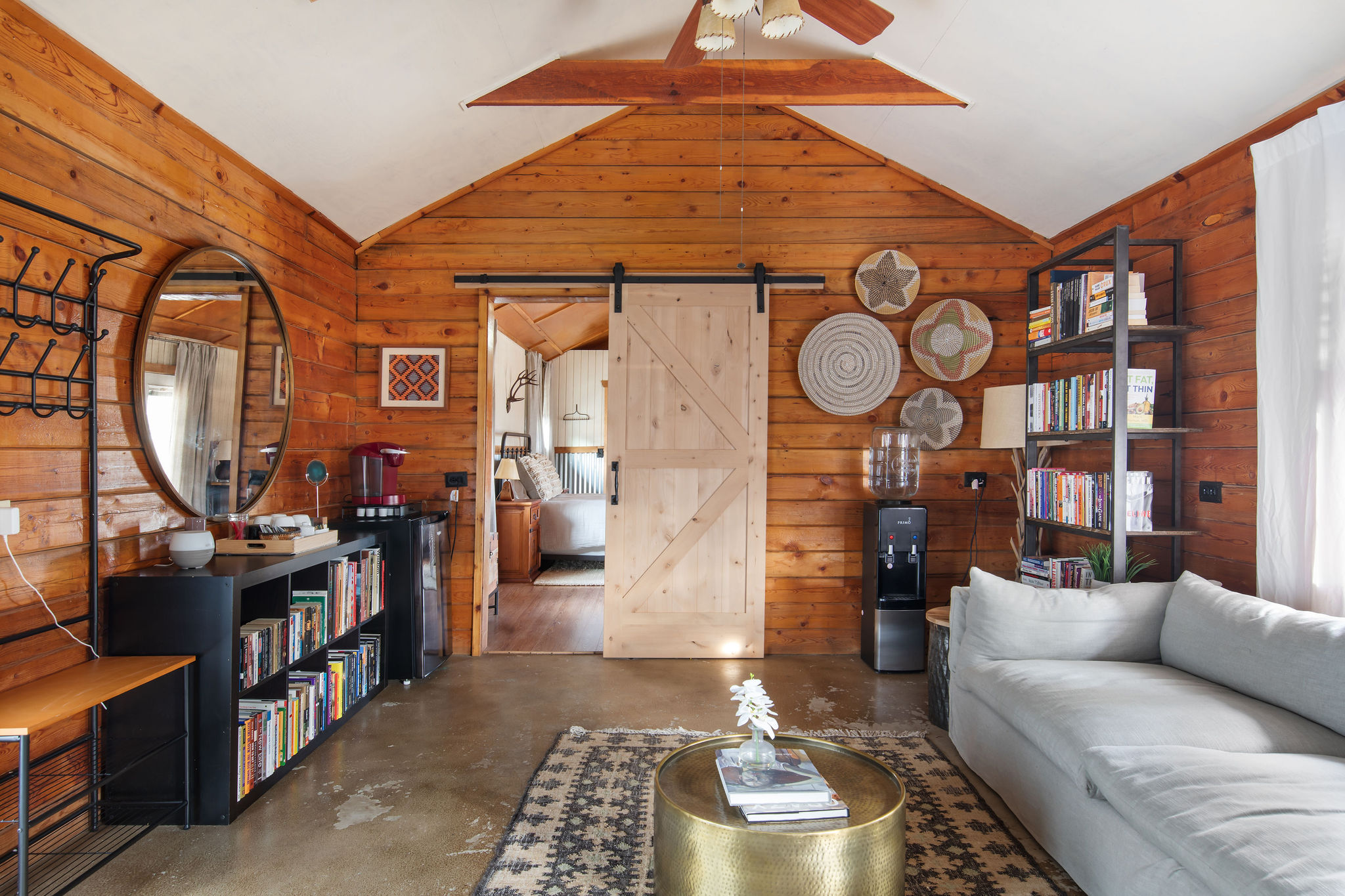 The back cabin living area — log walls, a sofa, and a wall of books