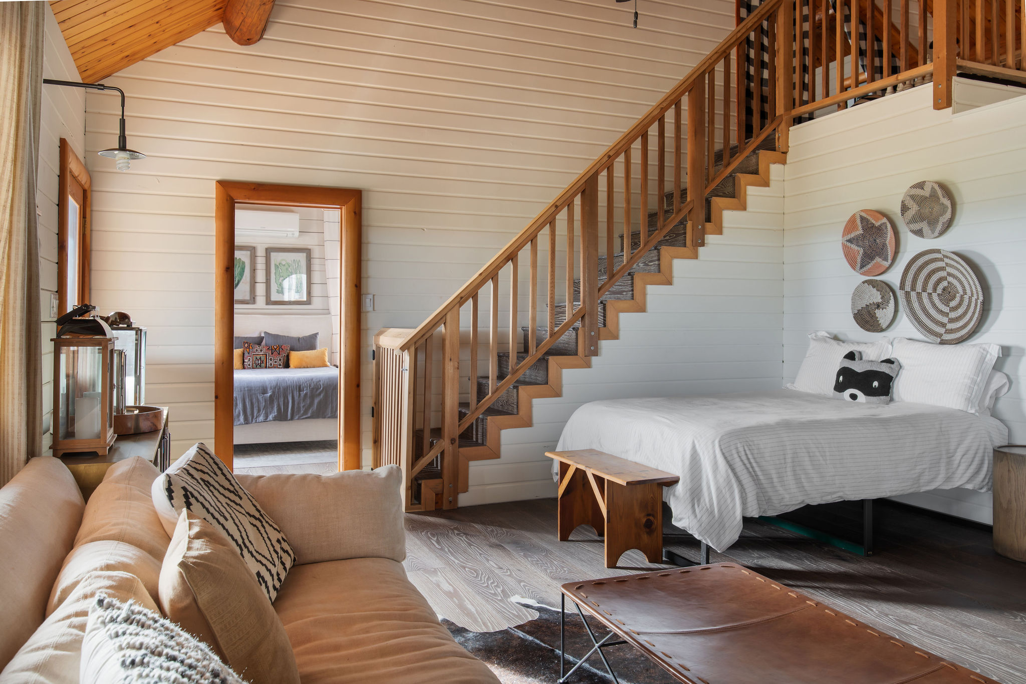 The living-room lounge — sofas, the stair to the twin loft, and the shared queen